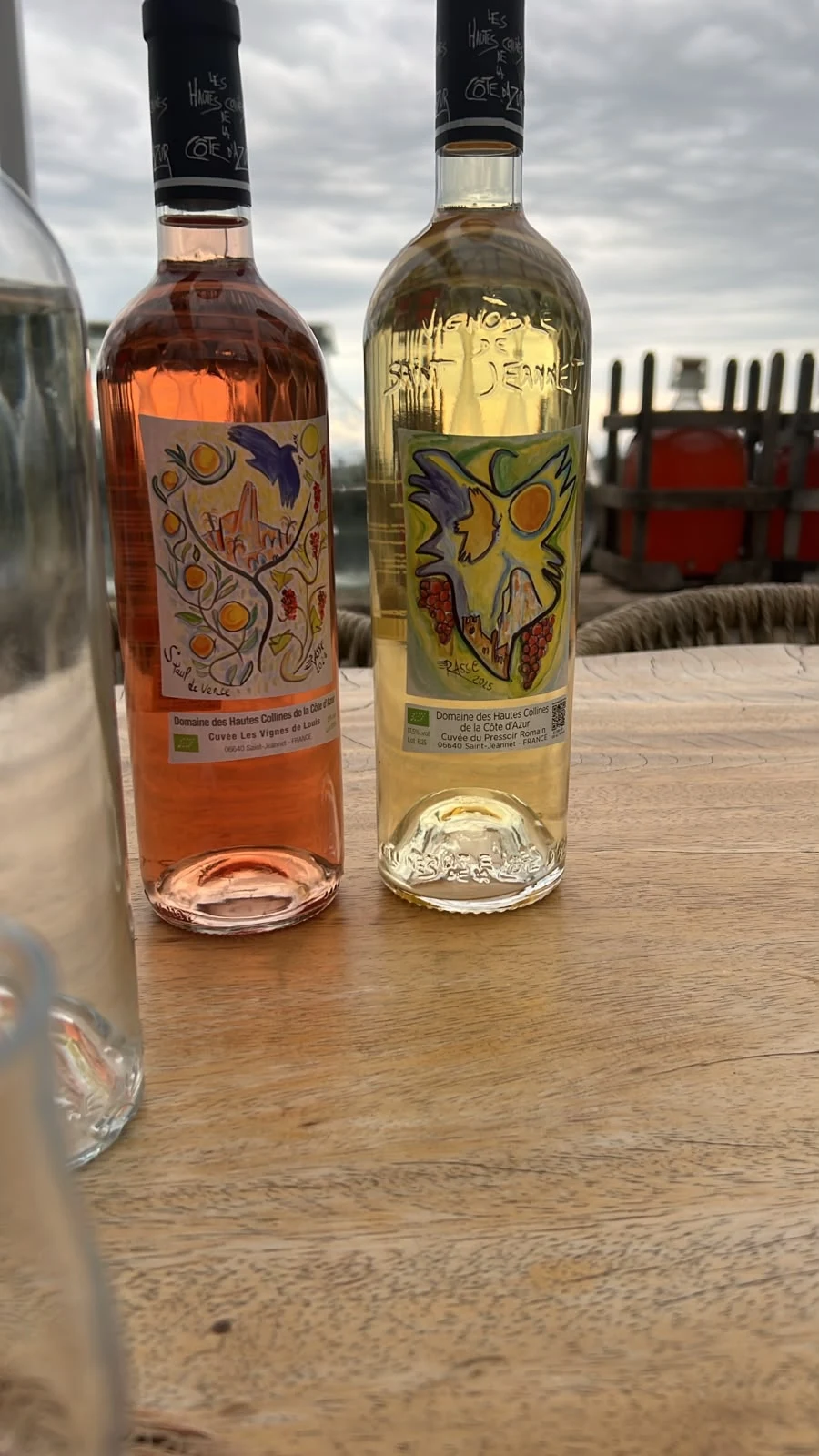 Rosé- und Weißweinflasche Les Vignes de Louis auf einem Holztisch.
